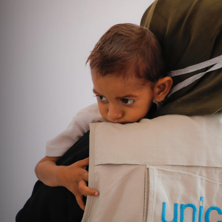 Kind op schouder van UNICEF-medewerker